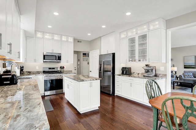 9653 Cypress Way, Carmel, IN 46032 - kitchen featuring appliances with stainless steel finishes, dark wood-style flooring, light stone counters, a kitchen island, and white cabinetry