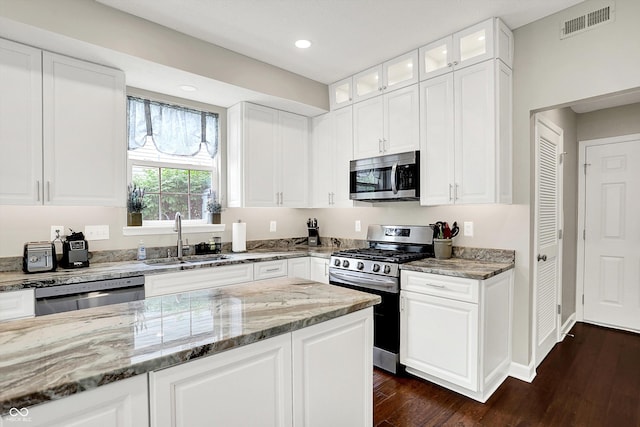 9653 Cypress Way, Carmel, IN 46032 - kitchen featuring stainless steel appliances, light stone counters, glass insert cabinets, dark wood finished floors, and recessed lighting