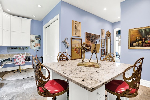 11557 Willow Springs Dr, Zionsville, IN 46077 - kitchen with a breakfast bar area, light stone counters, white cabinets, recessed lighting, and a center island
