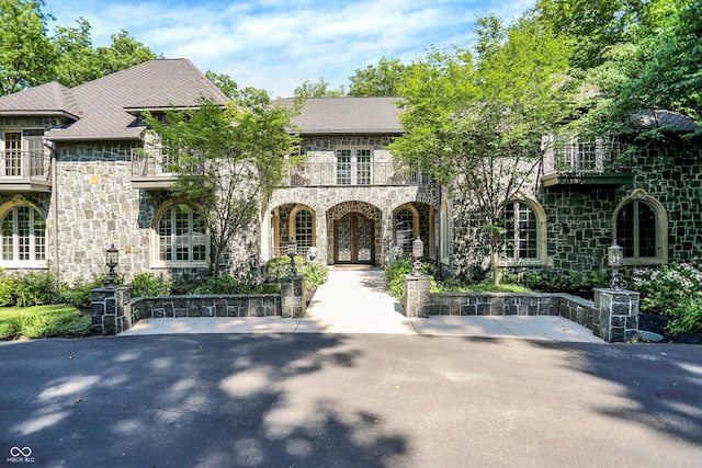 11557 Willow Springs Dr, Zionsville, IN 46077 - french country style house with stone siding, french doors, and a balcony