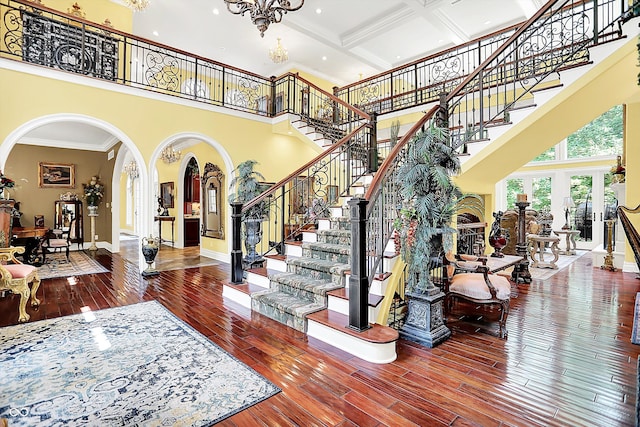 11557 Willow Springs Dr, Zionsville, IN 46077 - stairway featuring arched walkways, a high ceiling, hardwood / wood-style flooring, a chandelier, and ornamental molding