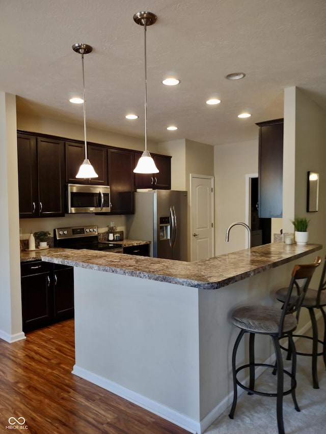 5932 Edelle Dr, Indianapolis, IN 46237 - kitchen featuring appliances with stainless steel finishes, recessed lighting, dark wood finished floors, dark brown cabinets, and hanging light fixtures