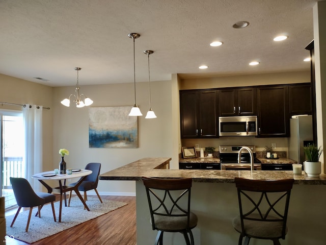 5932 Edelle Dr, Indianapolis, IN 46237 - kitchen with stainless steel appliances, a kitchen bar, dark wood-style flooring, recessed lighting, and dark brown cabinets
