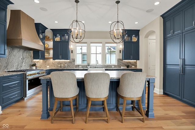 12839 Bird Cage, Carmel, IN 46032 - kitchen with custom range hood, stainless steel stove, blue cabinets, a chandelier, and a kitchen island
