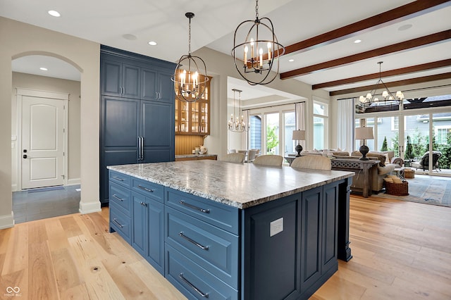 12839 Bird Cage, Carmel, IN 46032 - kitchen with a chandelier, arched walkways, blue cabinetry, a kitchen island, and open floor plan