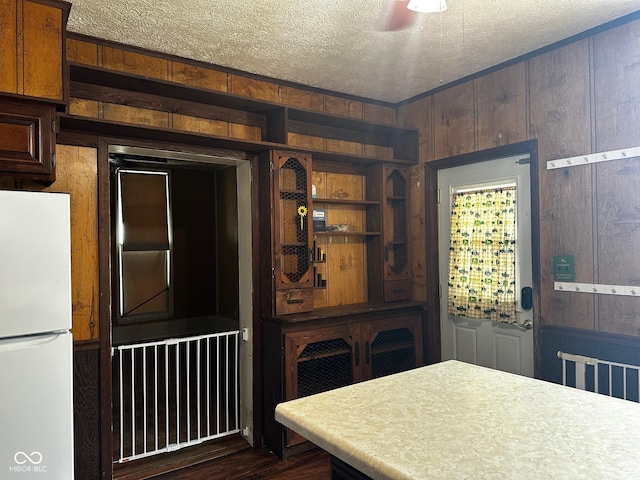 209 N Middle St, Spencer, IN 47460 - kitchen with freestanding refrigerator, a textured ceiling, wood walls, dark wood-type flooring, and light countertops