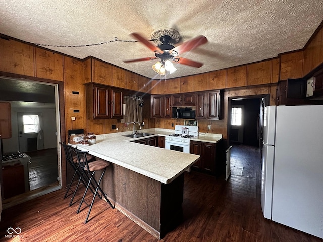 209 N Middle St, Spencer, IN 47460 - kitchen featuring white appliances, wood walls, a peninsula, light countertops, and dark wood finished floors