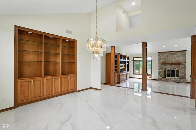 1326 Pebble Brook Dr, Noblesville, IN 46062 - unfurnished dining area featuring decorative columns, lofted ceiling, light marble finish flooring, a brick fireplace, and a chandelier