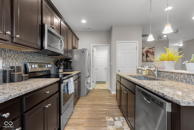2421 Creek Bank Dr, Columbus, IN 47201 - kitchen featuring stainless steel appliances, dark brown cabinetry, backsplash, light wood finished floors, and light stone counters