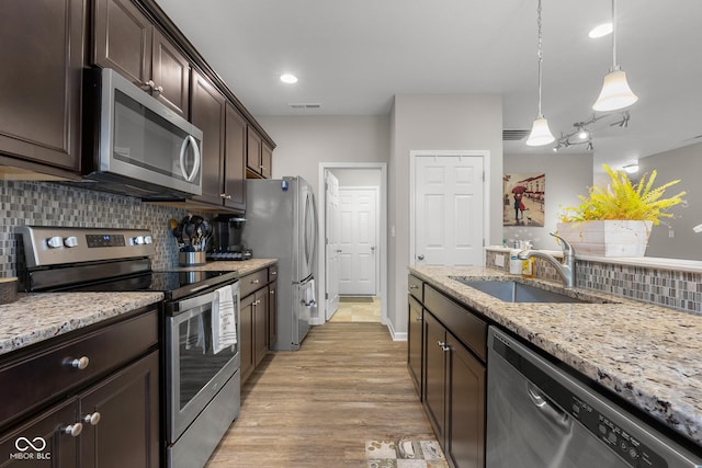 2421 Creek Bank Dr, Columbus, IN 47201 - kitchen with appliances with stainless steel finishes, dark brown cabinetry, decorative backsplash, light wood-style floors, and light stone counters