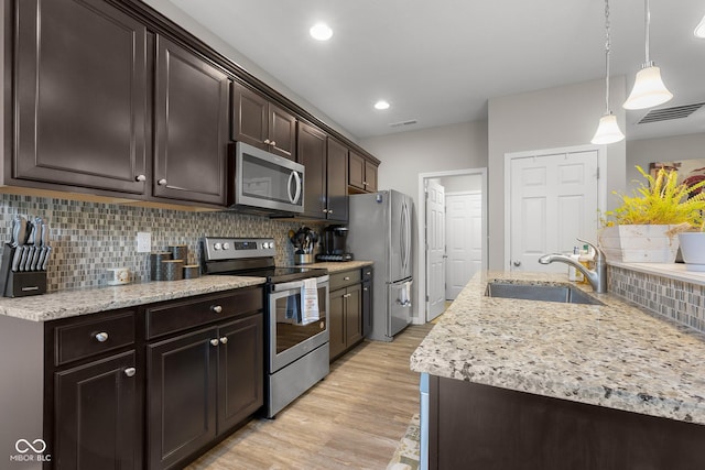 2421 Creek Bank Dr, Columbus, IN 47201 - kitchen featuring appliances with stainless steel finishes, dark brown cabinets, light wood-type flooring, backsplash, and light stone counters