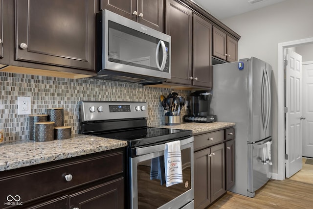 2421 Creek Bank Dr, Columbus, IN 47201 - kitchen with appliances with stainless steel finishes, dark brown cabinets, light wood finished floors, and decorative backsplash
