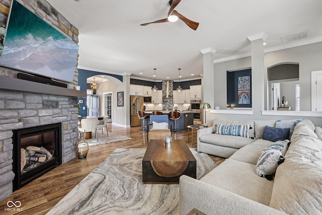 2105 Granville Dr, Westfield, IN 46074 - living room with ornamental molding, a ceiling fan, arched walkways, wood finished floors, and a stone fireplace