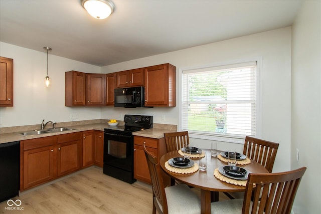 717 Berkeley Dr, Shelbyville, IN 46176 - kitchen featuring black appliances, brown cabinetry, light wood-type flooring, pendant lighting, and light countertops