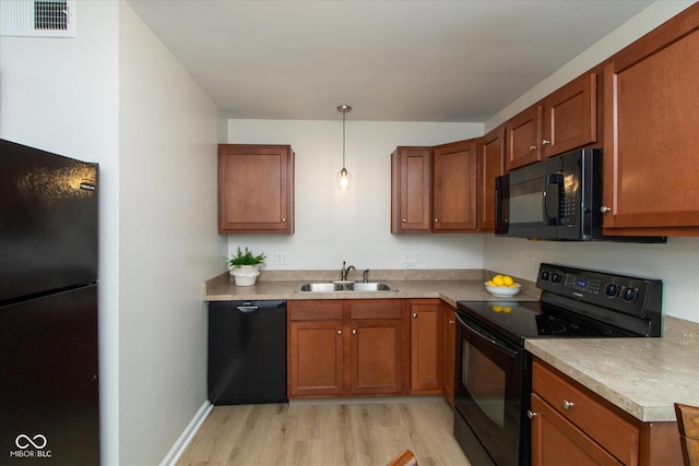 717 Berkeley Dr, Shelbyville, IN 46176 - kitchen with black appliances, light wood-style floors, brown cabinetry, hanging light fixtures, and light countertops