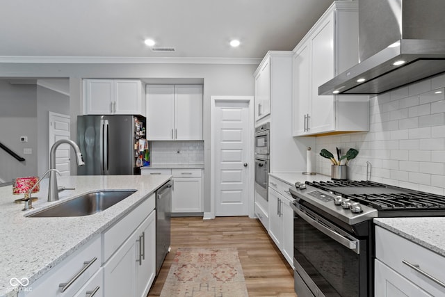 15546 Senita Ln, Fishers, IN 46037 - kitchen featuring wall chimney range hood, stainless steel appliances, white cabinetry, tasteful backsplash, and light wood finished floors