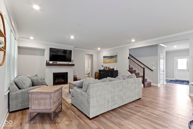 15546 Senita Ln, Fishers, IN 46037 - living room with stairs, a tiled fireplace, light wood-style flooring, recessed lighting, and ornamental molding