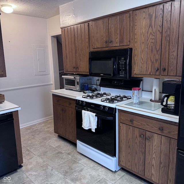 206 W 2nd St, Greensburg, IN 47240 - kitchen with black microwave, range with gas stovetop, light countertops, electric panel, and a textured ceiling