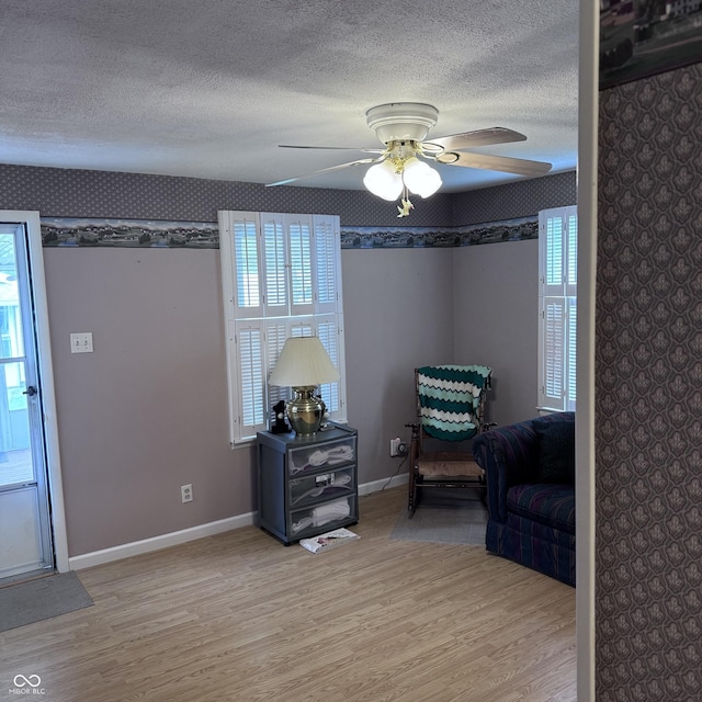 206 W 2nd St, Greensburg, IN 47240 - sitting room featuring wallpapered walls, light wood finished floors, a ceiling fan, a textured ceiling, and healthy amount of natural light