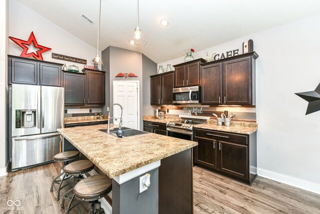 561 Farnham Dr, Westfield, IN 46074 - kitchen with stainless steel appliances, dark brown cabinets, vaulted ceiling, light wood-style floors, and a kitchen bar