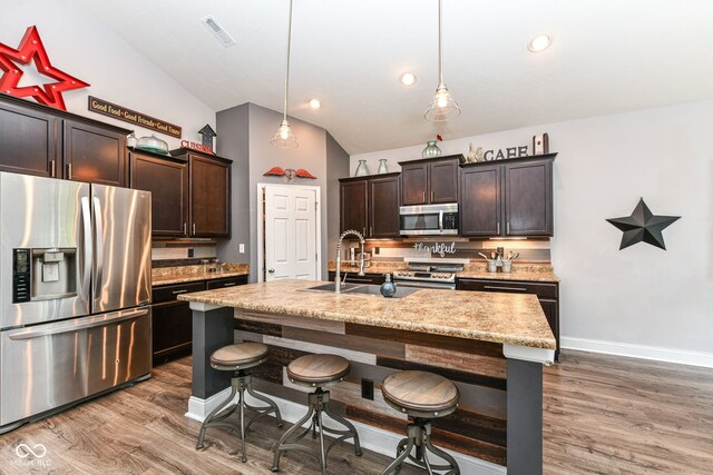 561 Farnham Dr, Westfield, IN 46074 - kitchen featuring stainless steel appliances, wood finished floors, vaulted ceiling, dark brown cabinets, and recessed lighting
