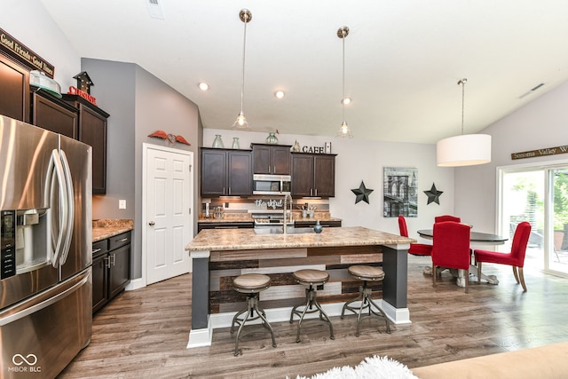 561 Farnham Dr, Westfield, IN 46074 - kitchen with appliances with stainless steel finishes, lofted ceiling, light wood-type flooring, a breakfast bar, and dark brown cabinetry