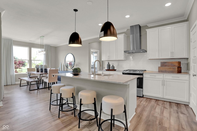 17030 Daly Dr, Noblesville, IN 46062 - kitchen with wall chimney range hood, stainless steel gas range, light wood-style flooring, a breakfast bar area, and ornamental molding