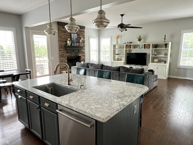 13895 Cloverfield Cir, Fishers, IN 46038 - kitchen with dishwasher, dark wood-type flooring, a ceiling fan, a fireplace, and a kitchen island with sink