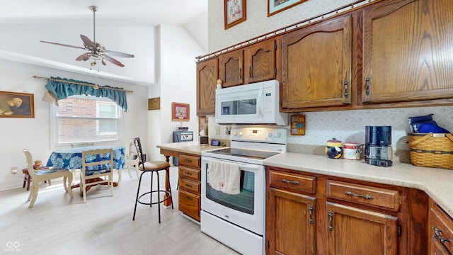 1067 Acadia Ct, Indianapolis, IN 46217 - kitchen featuring white appliances, brown cabinets, tasteful backsplash, a ceiling fan, and high vaulted ceiling