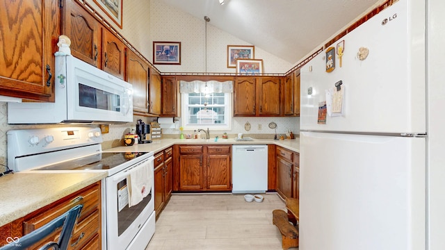 1067 Acadia Ct, Indianapolis, IN 46217 - kitchen featuring white appliances, lofted ceiling, brown cabinetry, light wood-style flooring, and light countertops