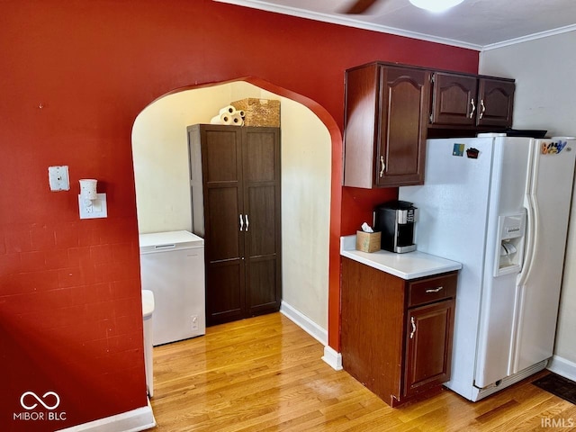 313 S Brittain Ave, Muncie, IN 47303 - kitchen featuring white refrigerator with ice dispenser, arched walkways, light countertops, light wood-style floors, and crown molding