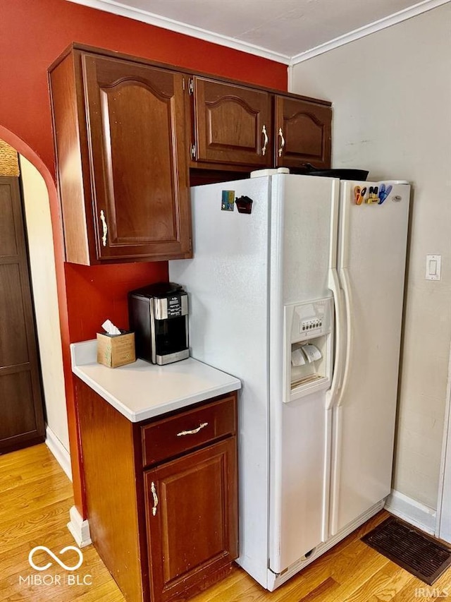313 S Brittain Ave, Muncie, IN 47303 - kitchen with white fridge with ice dispenser, light countertops, light wood finished floors, arched walkways, and ornamental molding