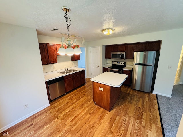 5938 Tybalt Ln, Indianapolis, IN 46254 - kitchen with stainless steel appliances, light countertops, a textured ceiling, light wood-style floors, and a center island
