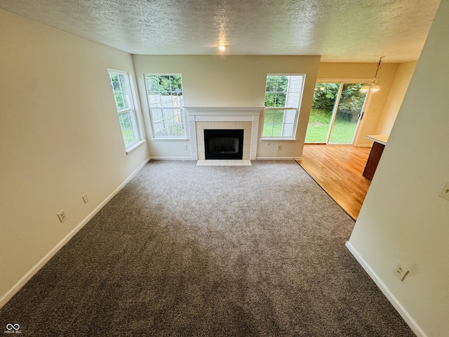 5938 Tybalt Ln, Indianapolis, IN 46254 - unfurnished living room featuring carpet flooring, a textured ceiling, healthy amount of natural light, and a fireplace
