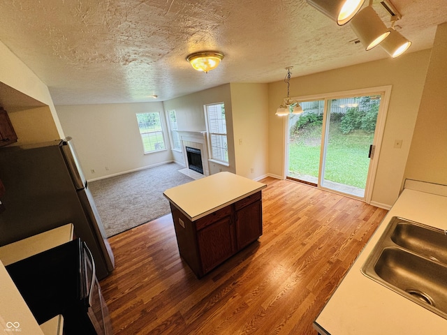 5938 Tybalt Ln, Indianapolis, IN 46254 - kitchen featuring light wood finished floors, a fireplace, freestanding refrigerator, dark brown cabinets, and a textured ceiling