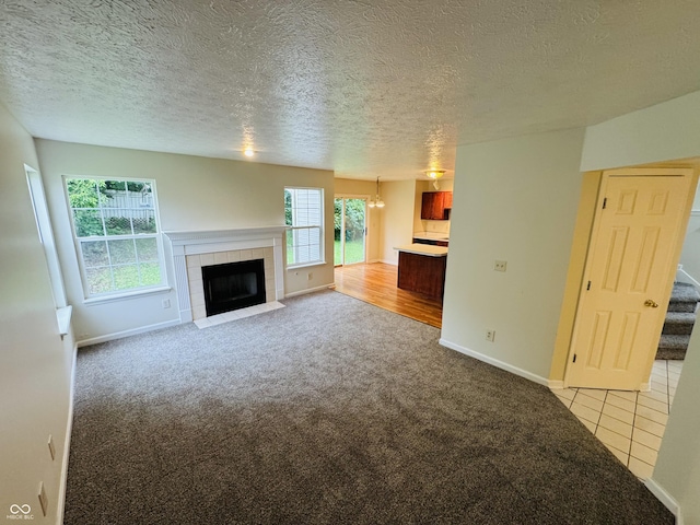 5938 Tybalt Ln, Indianapolis, IN 46254 - unfurnished living room with a tiled fireplace, a chandelier, light carpet, stairway, and a textured ceiling