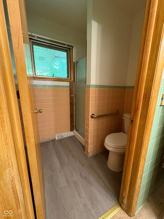 4609 Andover Rd, Indianapolis, IN 46226 - full bath with tile walls, wood finished floors, a shower stall, and a wainscoted wall