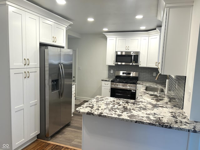 2631 Mcleay Dr, Indianapolis, IN 46220 - kitchen featuring appliances with stainless steel finishes, dark wood-style flooring, a peninsula, decorative backsplash, and recessed lighting