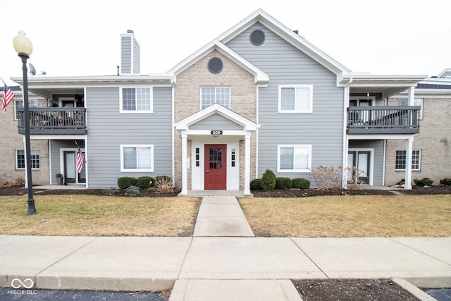 209 Faulkner Ct Unit 102, Carmel, IN 46032 - townhome / multi-family property featuring a front lawn, a balcony, a chimney, and brick siding
