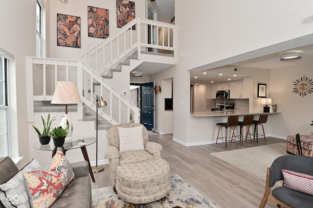 9477 Aberdare Dr N, Indianapolis, IN 46250 - living room featuring stairway, light wood-style flooring, and a towering ceiling