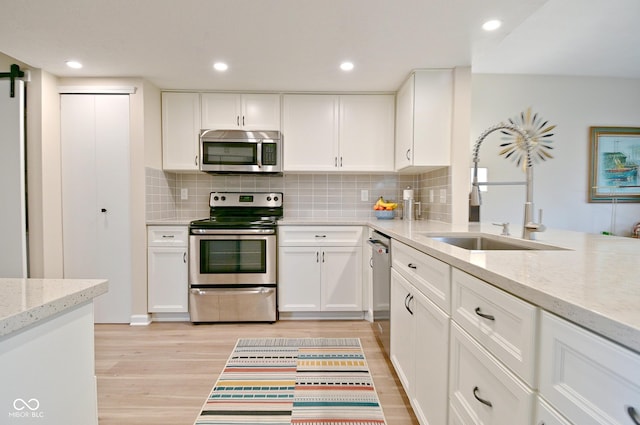 9477 Aberdare Dr N, Indianapolis, IN 46250 - kitchen with appliances with stainless steel finishes, light wood finished floors, white cabinets, backsplash, and recessed lighting