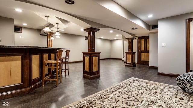 7743 Camelback Dr, Indianapolis, IN 46250 - indoor dry bar featuring dark wood finished floors, decorative columns, arched walkways, recessed lighting, and pendant lighting