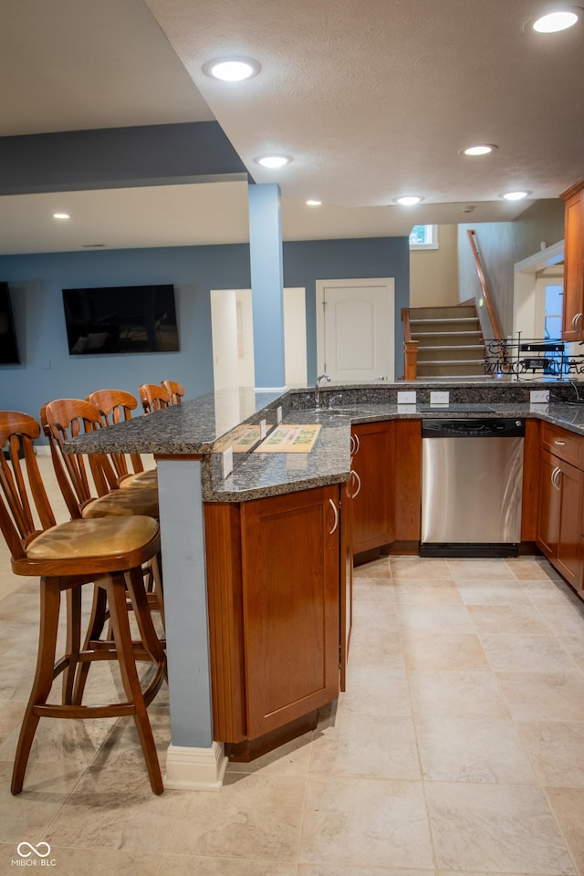 23119 Sonoma Ln, Cicero, IN 46034 - kitchen featuring stainless steel dishwasher, brown cabinets, a breakfast bar area, dark stone counters, and recessed lighting