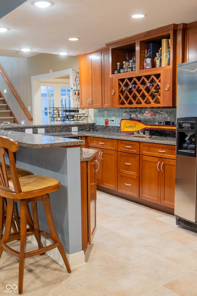 23119 Sonoma Ln, Cicero, IN 46034 - kitchen with stainless steel fridge with ice dispenser, a breakfast bar area, backsplash, french doors, and brown cabinetry