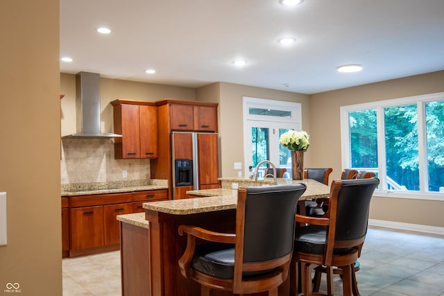 23119 Sonoma Ln, Cicero, IN 46034 - kitchen featuring paneled fridge, wall chimney exhaust hood, brown cabinetry, recessed lighting, and a breakfast bar area
