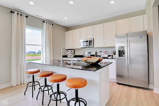 16876 Daly Dr, Noblesville, IN 46062 - kitchen featuring appliances with stainless steel finishes, light wood-type flooring, a kitchen island with sink, recessed lighting, and white cabinetry