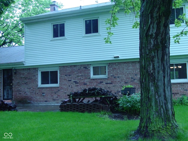 1808 Orchid Ct, Indianapolis, IN 46219 - view of side of property featuring brick siding, a lawn, and a chimney