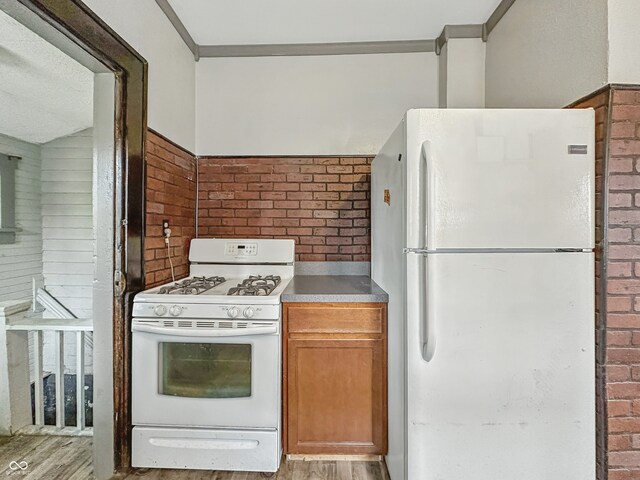 1011 W 7th St, Anderson, IN 46016 - kitchen featuring white appliances, brick wall, light wood finished floors, brown cabinetry, and crown molding
