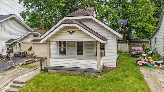 1011 W 7th St, Anderson, IN 46016 - view of front facade with driveway, a porch, a garage, a chimney, and a front lawn