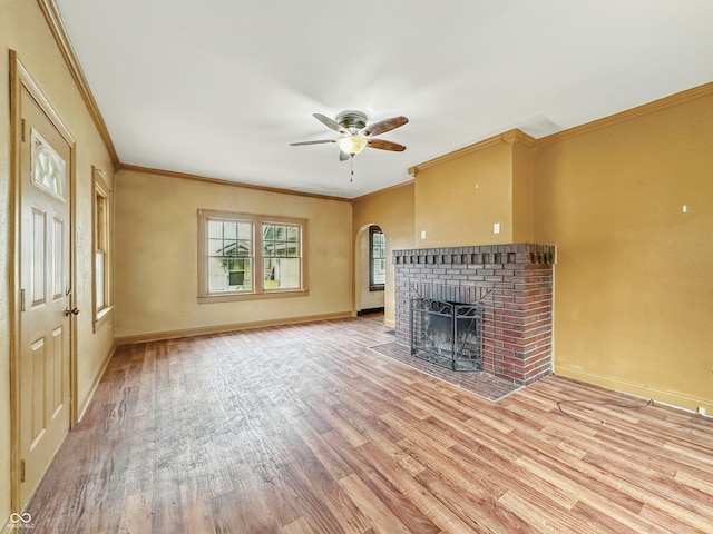 1011 W 7th St, Anderson, IN 46016 - unfurnished living room featuring light wood-style floors, ceiling fan, crown molding, a fireplace, and arched walkways